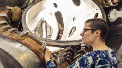 Former graduate student Alexandra LeViness has her hand on a section of a stellarator, a twisty fusion device.